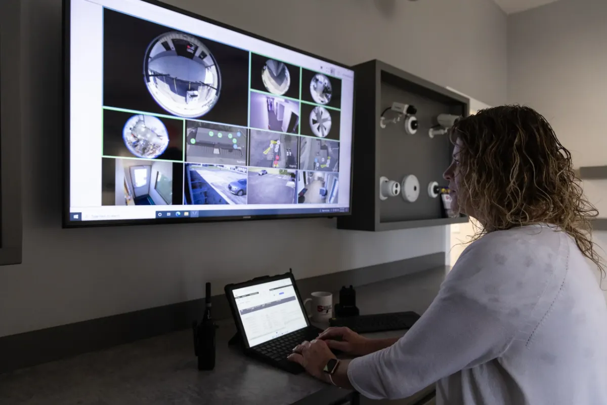 Security technician monitoring integrated access control system with live surveillance camera feeds and system management software for unified commercial security.